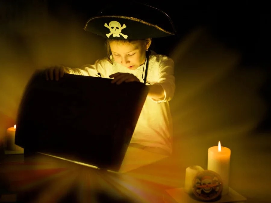 enfant déguisé en pirate ouvrant un coffre à trésors